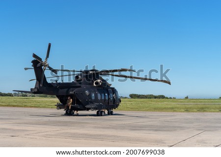 A modern American military helicopter, ready to fly for a tactical operation, is on the runway.