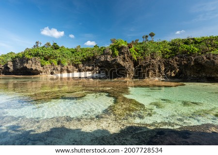 Stunning scene, natural emerald green sea pool forming at low tide, cliff full of coastal vegetation, blue sky. Iriomote Island.  Royalty-Free Stock Photo #2007728534