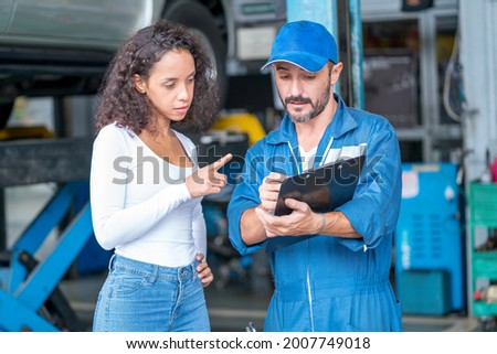 Auto services and Small business concepts. Customer and mechanic with checklist discussing work in auto service center. Royalty-Free Stock Photo #2007749018
