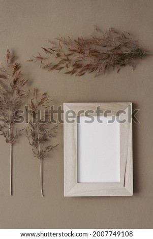 An empty wooden picture frame and plants on a brow vintage background. Flat lay, image background. 