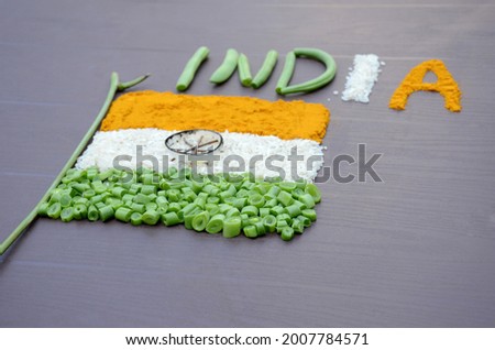 closeup orange turmeric,white rice , green beans vegetable with writing india indian flag memorial day or veteran's day on the brown background.