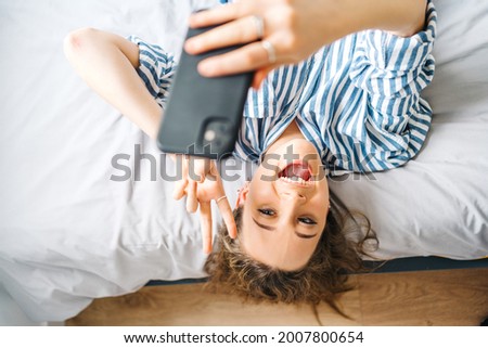 positive beautiful young woman relaxing on bed in modern apartment 