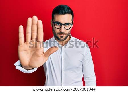 Young hispanic businessman wearing shirt and glasses doing stop sing with palm of the hand. warning expression with negative and serious gesture on the face.  Royalty-Free Stock Photo #2007801044