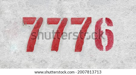 Red Number 7776 on the white wall. Spray paint. Number seven thousand seven hundred and seventy six.
