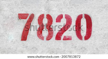 Red Number 7820 on the white wall. Spray paint. Number seven thousand eight hundred and twenty.