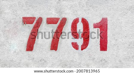 Red Number 7791 on the white wall. Spray paint. Number seven thousand seven hundred and ninety one.