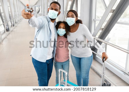Runway Selfie. African American Family Of Three Wearing Disposable Face Masks Taking Selfportait Picture With Gadget In Airport Terminal, Travelling Together During Covid Pandemic, Selective Focus