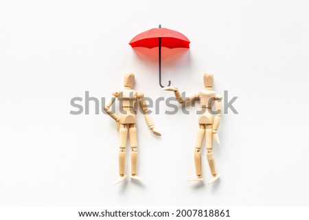 Life health financial protection - wooden mannequin figures and umbrella