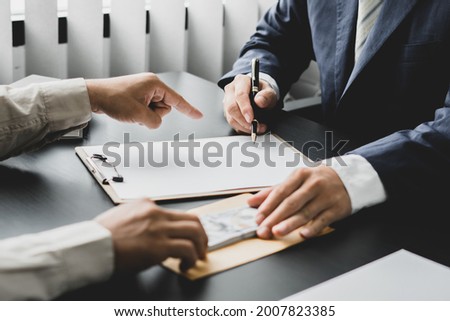 Hands of businessmen agreeing to the offer of bribery by signing a personal benefit agreement The concept of fraud and business practices within the company