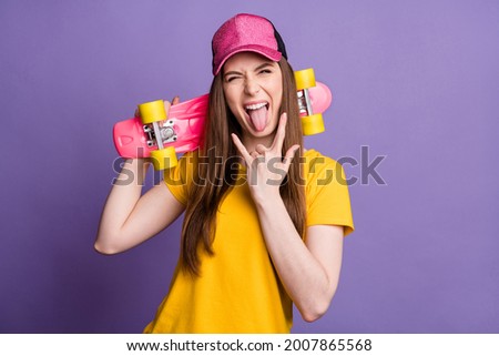 Photo of crazy happy cheerful young woman make fingers rock sign hold longboard isolated on violet color background