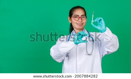 Asian female doctor wearing lab coat holding syringe and Covid 19 vaccine vial bottle smiling. Concept for Covid 19 vaccination.