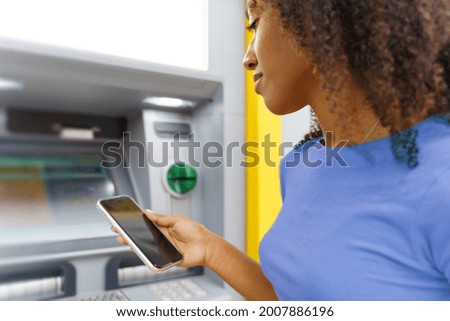 One black woman withdrawing money at an atm Royalty-Free Stock Photo #2007886196