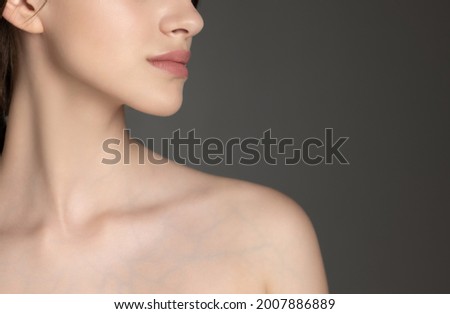 Close-up portrait of beautiful caucasian girl with tender neck and clavicle isolated on gray studio background. Concept of female beauty, tenderness Royalty-Free Stock Photo #2007886889
