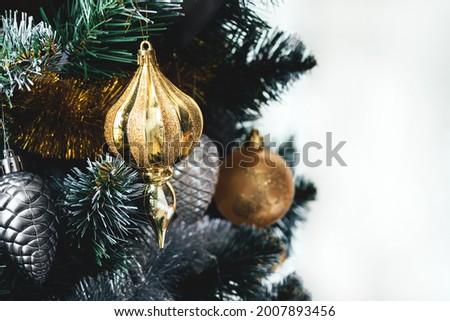 Golden toy and other decorations hanging on Christmas tree with tinsel garland on white background. Holiday banner with copy space. Selective focus