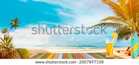 Panoramic tropical sea view with the sunny day. On the table are drinks and tropical fruits. A fun summer vacation getaway with outdoor activities, swimming, surfing, volleyball, and beach parties.
