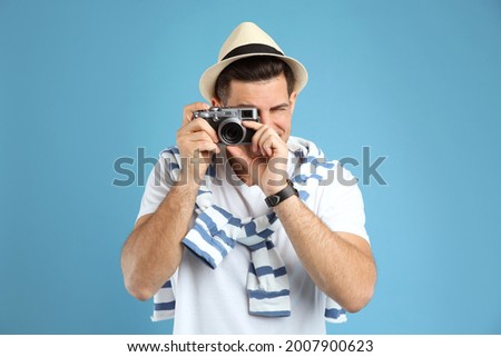 Male tourist taking picture on turquoise background