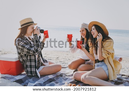 Full body three friends fun young women in straw hat summer clothes have picnic hang out take photo drink liguor glasses raise toasts outdoors on sea beach background People vacation journey concept