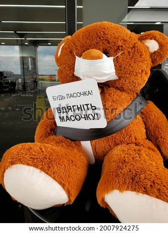 Toy bear in medical mask. Teddy bear holding alert sign and wearing face mask protective for spreading of disease virus. Text - please put on mask