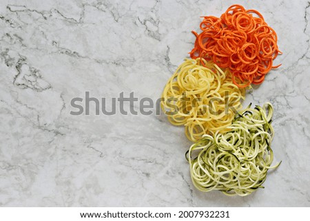 Raw vegetable spaghetti. Zucchini, carrot and potato pasta. Flat layot, copy space