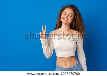 Portrait of a young funny woman showing peace gesture