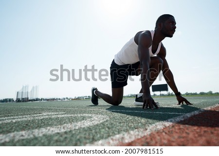 Photo below. African American athlete runner stands at the start of the race. Active sport concept
