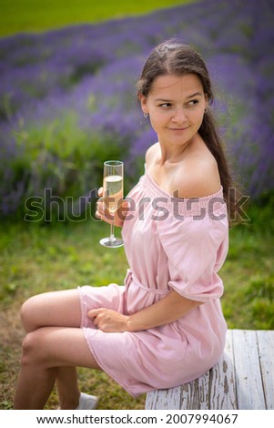 Beautiful young woman resting on a lavender field with glass of champagne in Czech republic