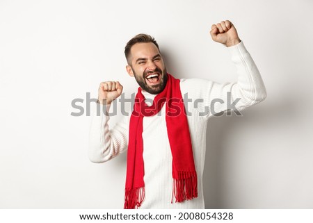 Happy bearded man celebrating christmas holidays on party, dancing and pointing fingers, standing over white background