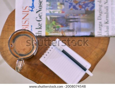 top view of a cup black coffee, notebook and newspaper on the table.