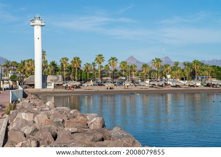 Lighthouse on the malecon with palm trees and rocks in a sunny morning with blue calm water in the bay of Loreto in Baja California Sur. Mexico Royalty-Free Stock Photo #2008079855