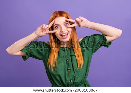 Photo of impressed red hair young lady show v-sign wear green open shoulders blouse isolated on violet color background