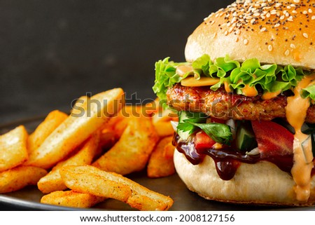 Extra Close-up of Fresh tasty burger with chicken, salad, cheesee, sauces and with french fries. Fat unhealthy street food.