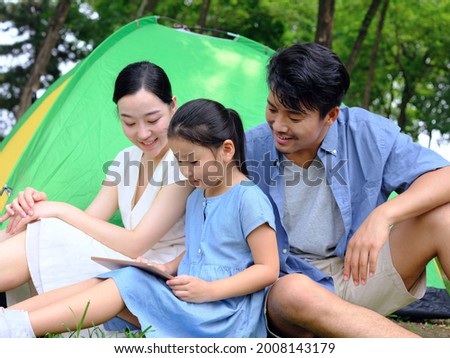 Happy family of three uses tablet computer outdoors high quality photo