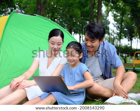 Happy family of three use computer to surf the Internet outdoors high quality photo