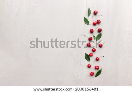 Flat lay top view on gray concrete background with sweet cherry berries and ice cubes. Freshness, summer conceptual minimal background. Eco, bio farm food and fruits concept with copy space area