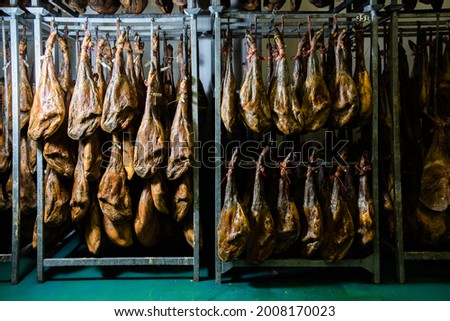 many Iberian Pata Negra hams hung ready to be sold in a warehouse. Jamón serrano. A Spanish ham. Red tag, red label. Iberian Ham Royalty-Free Stock Photo #2008170023