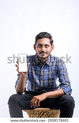 young indian man showing Smartphone over white background.