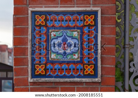 Fragment of the decoration of the facade of an old building in the form of ceramic tiles with a floral pattern