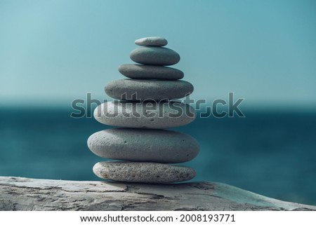 Balanced pebble pyramid on the beach on a sunny day. Abstract Sea bokeh on the background. Selective focus. Zen stones on the sea beach, meditation, spa, harmony, calmness, balance concept
