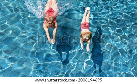 Happy family in swimming pool. Child with young woman swim, dive in pool with fun - jump deep down underwater. Healthy lifestyle, people water sport activity, swimming lessons on holidays with kids.