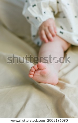 Close-up of the legs and arms of a little girl 8 months old on a beige background. Cozy.