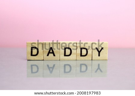 Daddy word made of wooden letters on a pink background