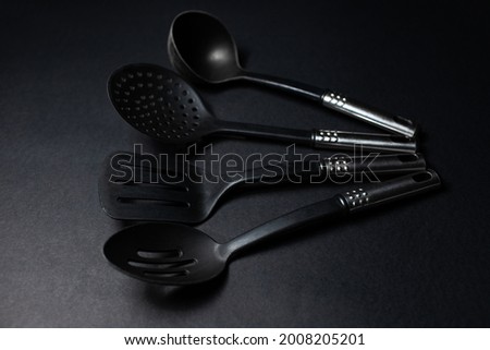 Studio picture of black eco plastic kitchen utensils, on the dark table.