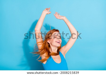 Photo of charming dreamy young woman wear top singlet wind blowing smiling rising arms isolated blue color background Royalty-Free Stock Photo #2008215839