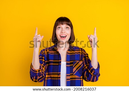 Portrait of attractive trendy cheerful girl pointing up copy empty space ad advert isolated over bright yellow color background