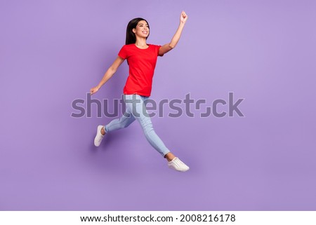 Full length profile photo of cute young brunette hairdo lady jump wear red t-shirt jeans isolated on violet color background
