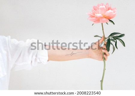 Woman with an arm tattoo holding a Peony The Fawn Royalty-Free Stock Photo #2008223540