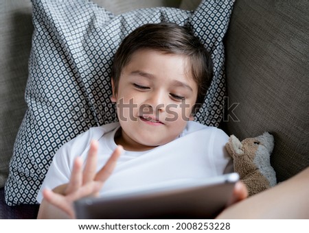School boy studying, learning online lesson at home, Happy child playing game or watching cartoon on tablet, Top view Cute kid with smiling face sitting on sofa relaxing in living room,Home schooling