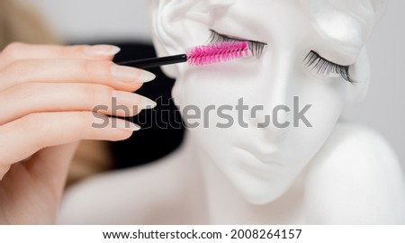 Concept woman eyelash extension practitioner uses brush for her daily care.