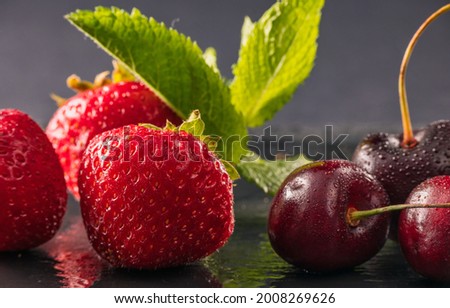 A still-life photo of fresh ripe fruits decorated with mint leaves on the dark background and reflections on a wet table. Natural products, harvest, nutrition, diet and indoor art decorations.