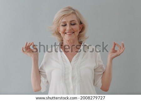 Elderly caucasian old aged woman portrait meditating and smiling with okay gesture